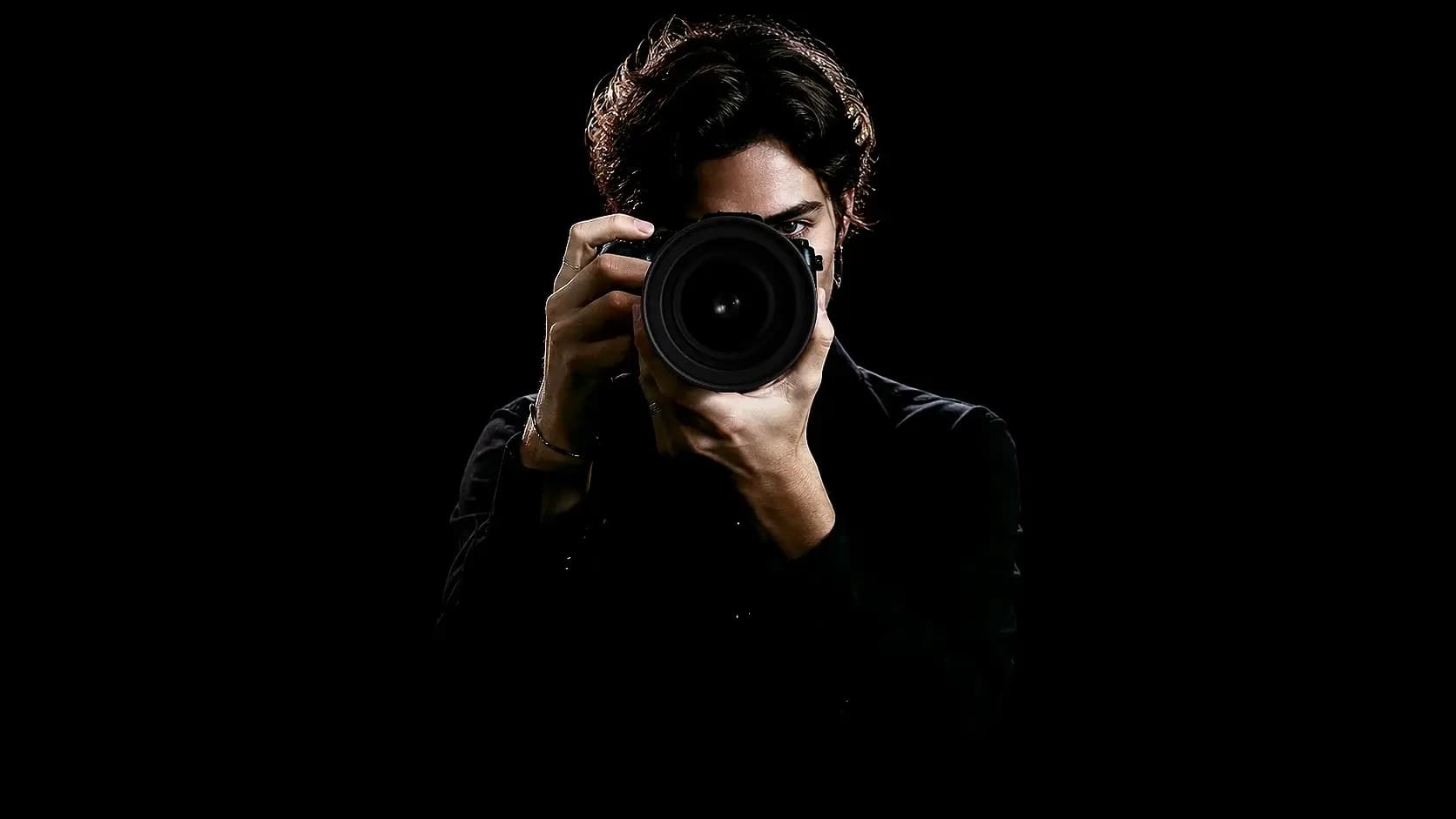 Un fotografo di moda punta la fotocamera direttamente verso lo spettatore