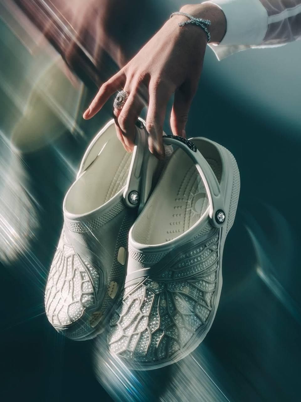 Have you seen the most unexpected collaboration of the season?
Crocs and Swarovski have teamed up to launch a limited-edition footwear collection, featuring luxurious Jibbitz and dazzling crystal embellishments that will outshine any accessory in your look!
What do you think about this bold style statement — the striking contrast between iconic “ugly shoes” and glamorous jewelry?