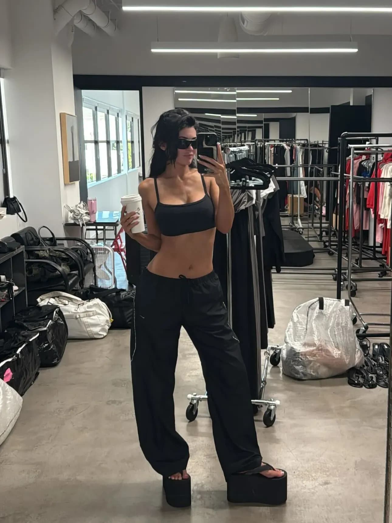 Kylie Jenner wears 5-inch ERL platform flip-flops with a bra top and joggers, turning everyday sandals into a bold summer fashion statement.