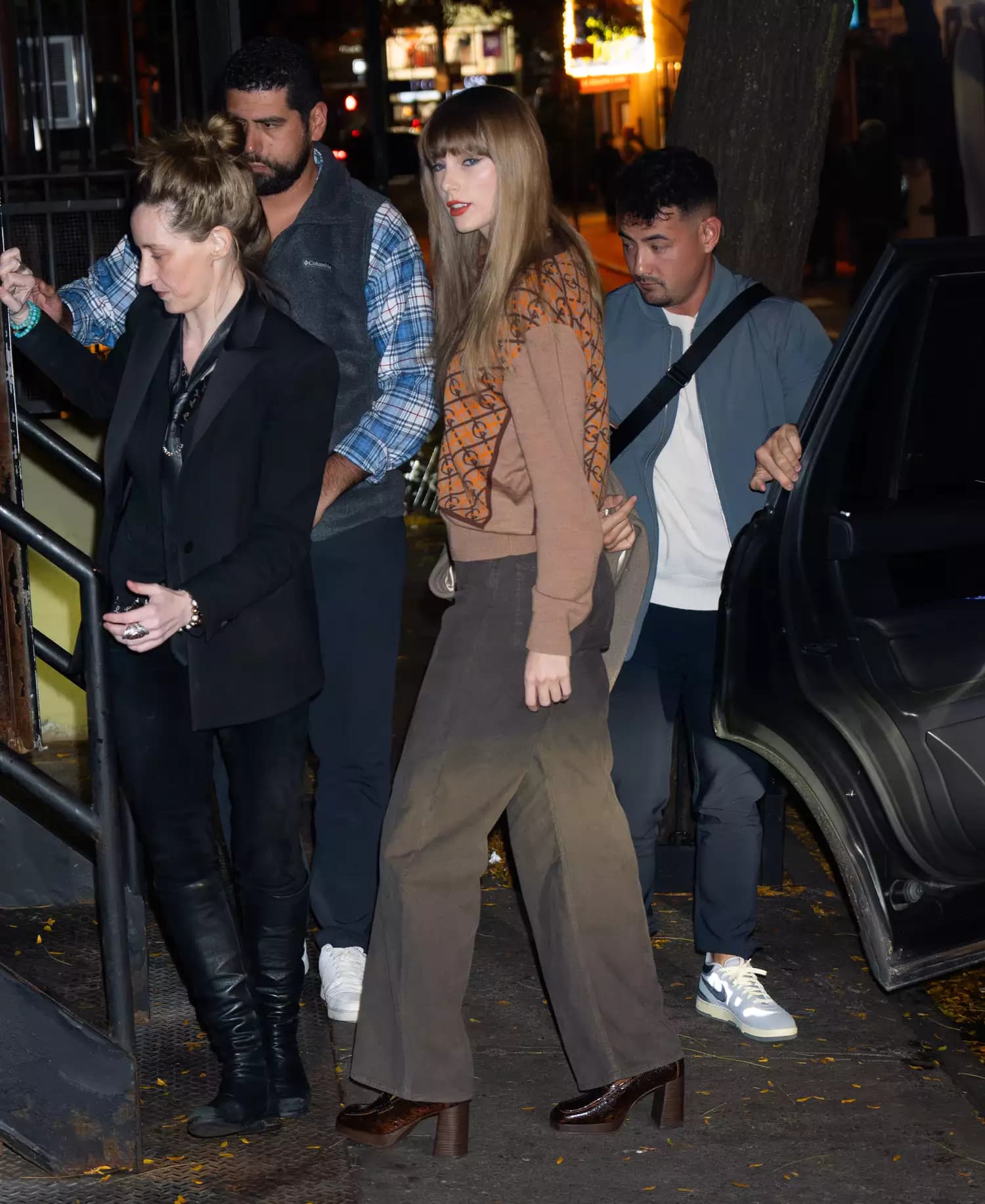 Taylor Swift stepped out in New York exuding a sophisticated aura with her monochromatic look that cleverly played with various shades of brown. The pop icon was spotted wearing a Gucci logo sweater in tan and chocolate, coordinating it perfectly with flared trousers and chunky penny loafers in a rich cocoa shade. Not stopping there, she upped the ante on her luxe appearance with a camel coat and a light tan satchel bag. Swift's look was completed with her classic red lip and sharp cat-eye, whil